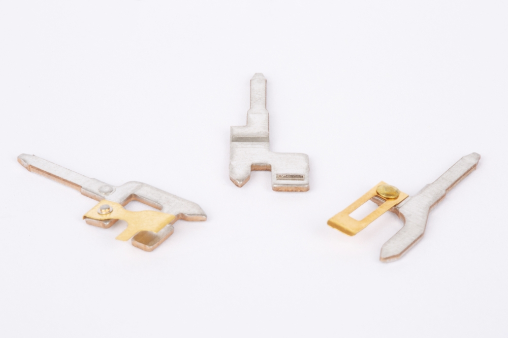 tiny electrical contact assemblies under 1" long, metal strip with electrical contact, custom contact assemblies, contact assembly with thin riveted blade with gold plating, contact assembly with welded contact wire metal blades, customized contact assemblies, includes contact blade stamping of tinned phosphor bronze metal strip, custom thin material stampings with progressive die stamping and reel-to-reel stamping, punch press punching metals from .003" thick with tight tolerance,