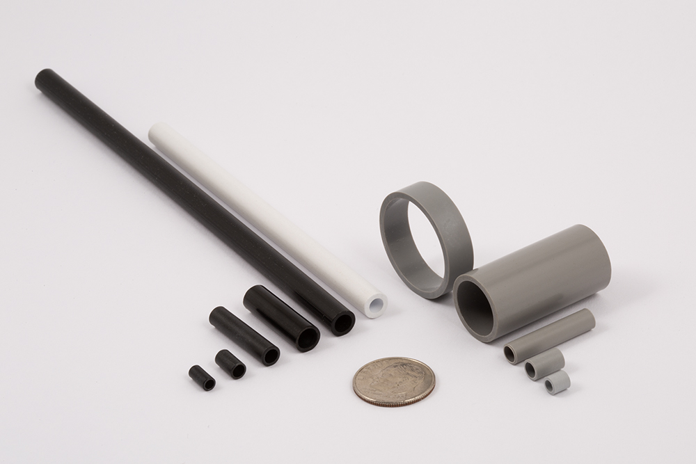 Black, white, and gray precision short and long insulator bushings for screws or tubing for switches. Available in of a variety of diameters and lengths, Bushing tube materials include Butyrate plastic, Resinite, rigid vinyl, convolute laminated, and cut to your specification, clean and burr-free. Any size up up to 1" diameter, tolerances as close as +/- .002", lengths from 1/8" to 1 1/2" long. Example of Precision Assemblies tubing used in insulating screws. Material is non-conductive, corrosion resistant, Custom ID, Custom OD, Custom lengths Dime for size reference.